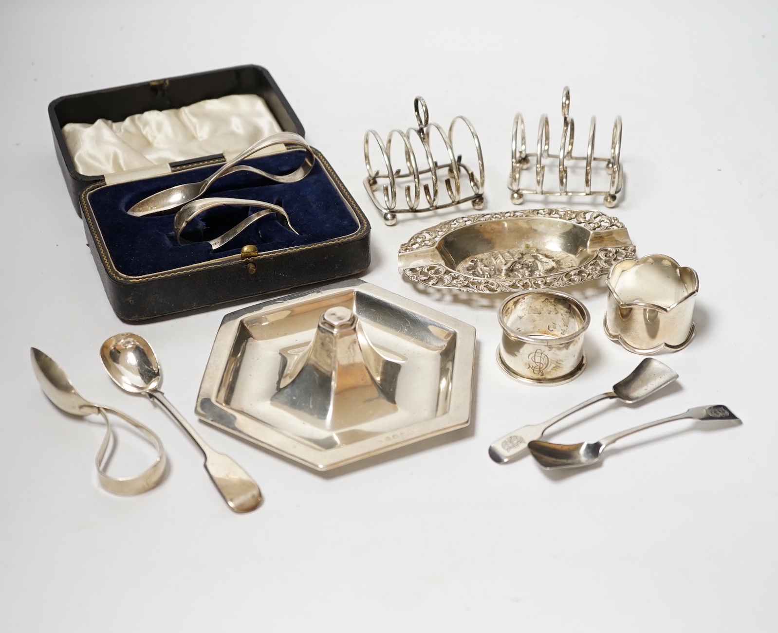 A Dutch white metal ashtray, with pierced border, 13.1cm and one other silver hexagonal ashtray?, a pair of small silver toastracks, two silver napkin rings and six items of silver flatware, including pair of Irish condi